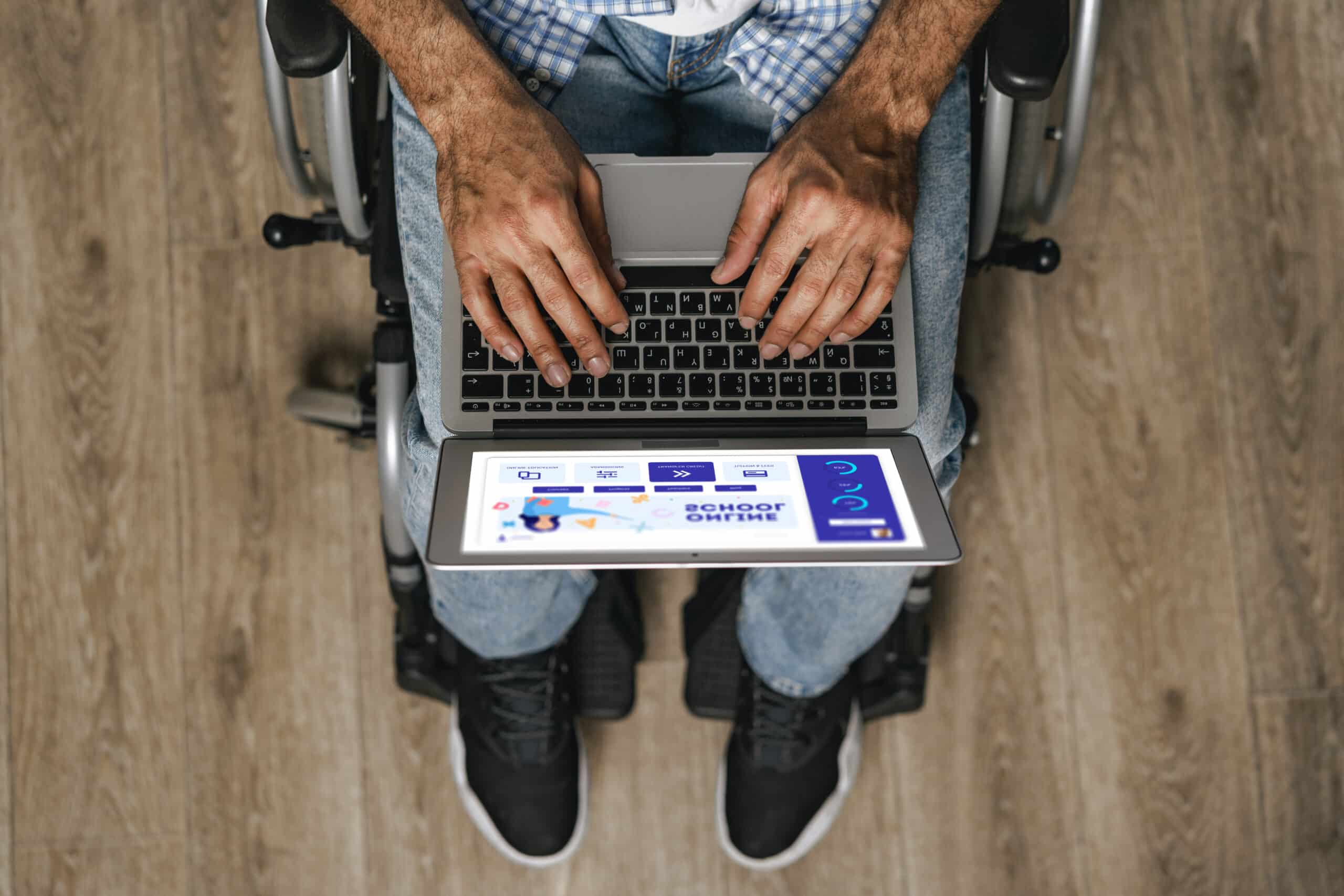 Homem utilizando laptop em cadeira de rodas representando a importância da acessibilidade de design UX para experiências digitais inclusivas.