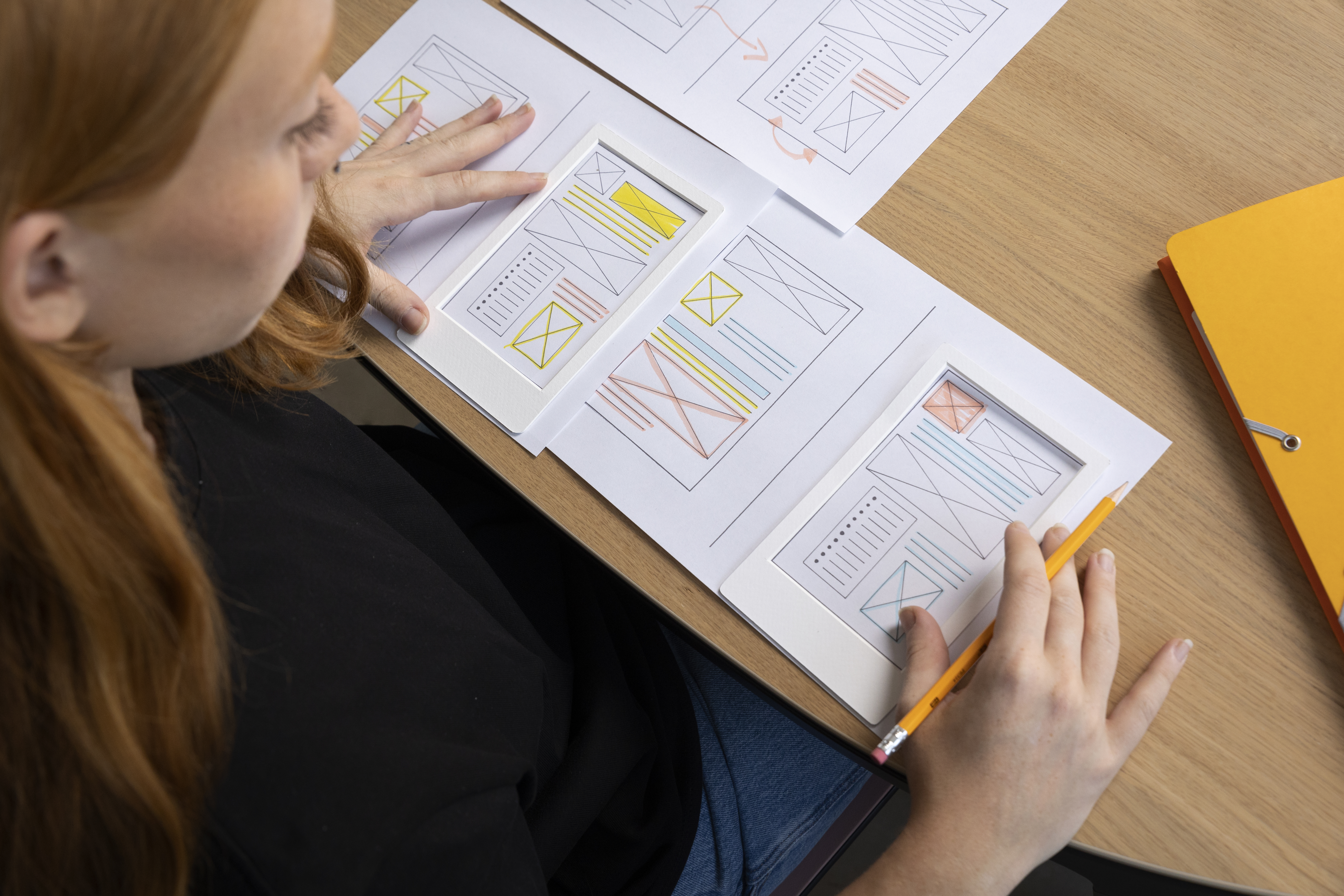 Designer analisando wireframes para compor um relatório de pesquisa UX claro e visual