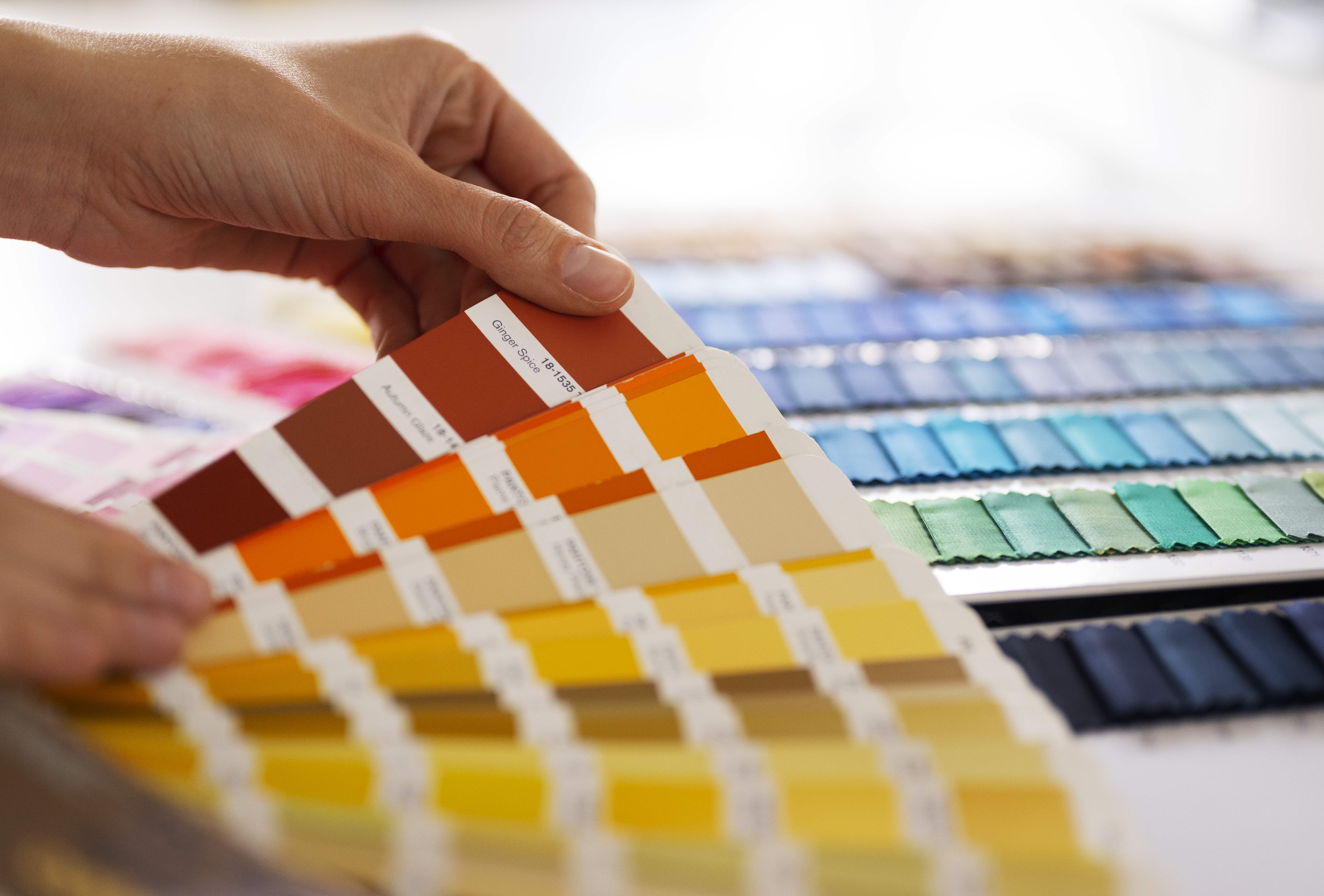 Mãos segurando uma paleta de amostras coloridas, representando a aplicação da teoria das cores no design gráfico e na experiência do usuário.